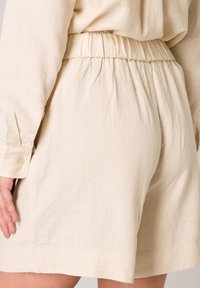 Lichtbeige linnen shorts met een elastische tailleband, met een losse pasvorm en een soepele textuur, die boven de knie eindigen met een nette zoom.