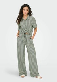 Lichtgroene, gestreepte twee-delige outfit met een gestrikte blouse met korte mouwen en wijde broekspijpen, met een relaxte pasvorm en zakken.