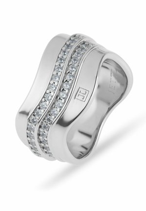 Brede zilveren ring met gebogen vorm, voorzien van twee rijen kleine heldere steentjes en een gegraveerd logo op de ringband.