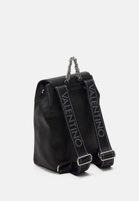 Svart läderryggsäck med en strukturerad form. Har ett vridet kedjehandtag och svarta remmar med "VALENTINO"-logotyp i grått.