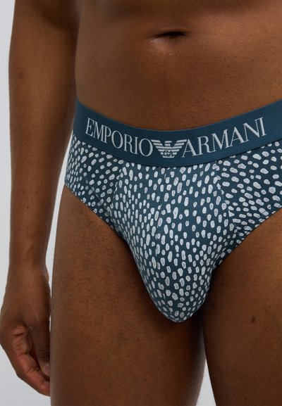 Pánské slipy Emporio Armani v tmavě tyrkysové barvě s bílým puntíkovaným vzorem a páskem s logem. Měkká látka, přiléhavý střih a elastický pas.