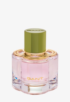Rosa Glasparfümflasche mit einem runden, grünen Deckel. Goldene Akzente umgeben den Hals und zeigen "GANT" in goldener Schrift auf dem Boden.