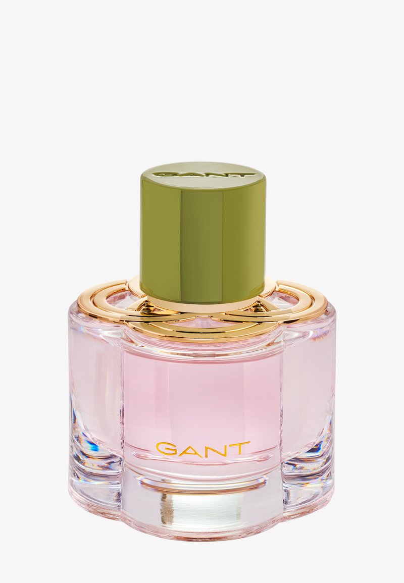 Pink glass perfume bottle with a round, green cap. Gold accents surround the neck, featuring "GANT" in gold text on the base.