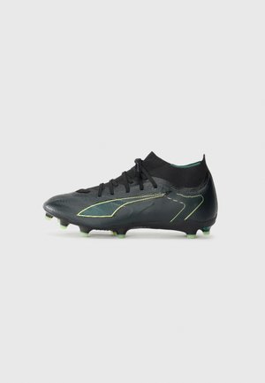 Black soccer cleat with a textured finish, featuring a snug ankle collar, black laces, and neon green sole studs. Accented with yellow lines.