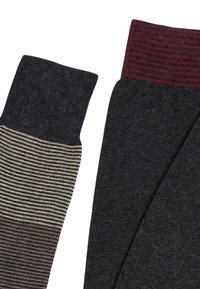 Due paia di calzini; uno ha un colore solido grigio scuro, l'altro presenta righe orizzontali nei toni del grigio e del beige con un bordo scuro.