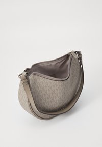 Sac à main en tissu doux de couleur marron avec un motif, fermeture à glissière et une bandoulière réglable. Présente un imprimé logo dans une teinte plus claire sur l'extérieur.