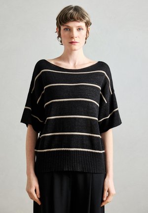 Pull en tricot noir avec des rayures horizontales beige, col large, manches courtes et poignets côtelés. Texture douce et coupe ample.