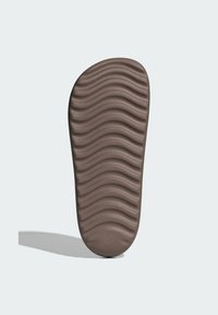 Brown shoe sole with a wavy textured pattern. Rounded shape with a smooth finish. Flat bottom suitable for various footwear designs.