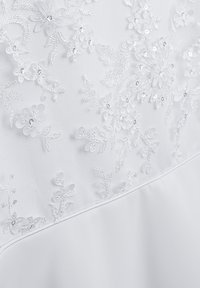 Weißer Stoff mit aufwändiger Blumenstickerei und Perlenakzenten, der ein strukturiertes Design mit filigranen Mustern über die gesamte Oberfläche schafft.
