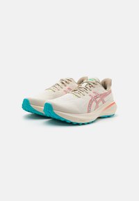 Lightweight running shoes with a beige mesh upper, vibrant turquoise outsole, and subtle pink detailing. Features laces and padded collar.