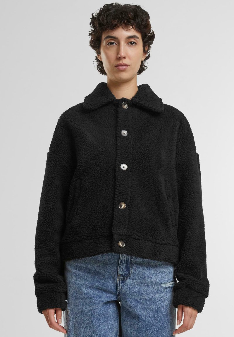 Zwarte sherpa-jack met een kraag, knopen aan de voorkant, zijzakken en een cropped ontwerp. Zachte textuur en ontspannen pasvorm.