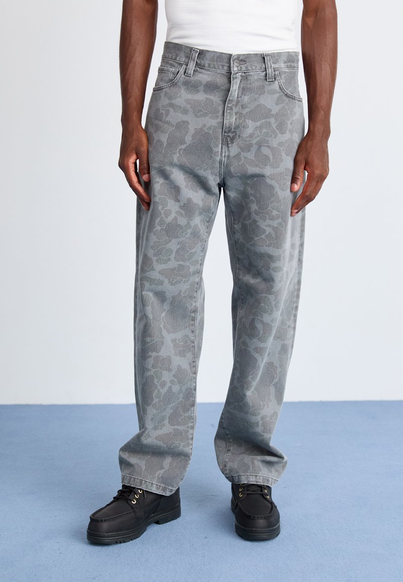 Grå camo-mønstret jeans med løs passform, med knapp- og glidelås-lukking, og brukt med svarte snørestøvler.
