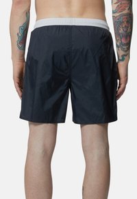 Pantaloncini da nuoto blu navy realizzati in tessuto leggero, dotati di una vita elastica con bordi bianchi a contrasto e una superficie liscia.