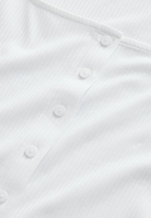 Witte, geribde stoffen shirt met een knoopsluiting en subtiele textuur. De knopen zijn rond en wit, met een eenvoudig ontwerp.
