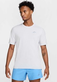 Camiseta deportiva blanca de manga corta con un logo azul claro; combinada con pantalones cortos azules. Tejido suave, con cuello redondo y corte relajado.