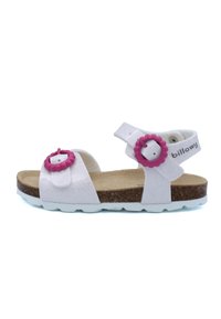 Sandales blanches avec finition scintillante, sangles ajustables, accents en forme de fleur rose et semelle en liège sur une semelle en caoutchouc blanche.