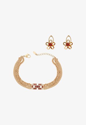 Złota bransoletka z zapięciem z czerwonym kamieniem szlachetnym oraz dopasowane złote kolczyki w kształcie kwiatu z czerwonymi kamieniami w centrum.