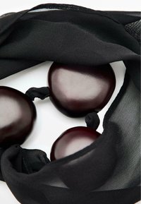 Tessuto nero trasparente avvolto attorno a tre sfere di un elegante bordeaux scuro, che mostrano superfici lisce e lucide con riflessi sottili.