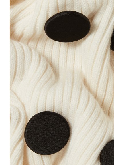 Tessuto bianco a coste caratterizzato da prominenti bottoni rivestiti in tessuto nero, che mette in mostra una texture morbida e un design allungato e ondulato.