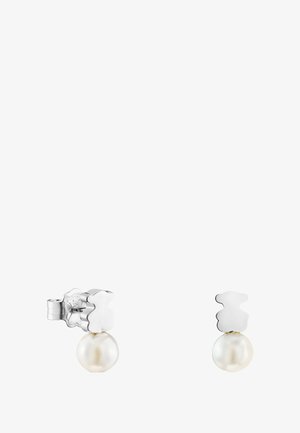 Srebrne kolczyki na sztyftach z motywem główek misiów, pod którymi zawieszone są pojedyncze, okrągłe, białe perły.