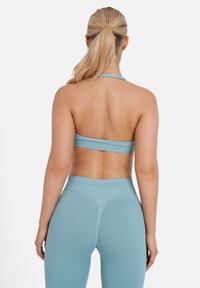 Top corto deportivo de color azul claro con tirantes finos y leggings de tiro alto a juego. Presenta una textura suave y un diseño ajustado.
