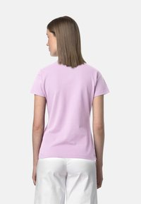 T-shirt a maniche corte, aderente, in cotone rosa chiaro, caratterizzato da un colletto a girocollo e una texture liscia. La vista posteriore mostra linee pulite e un design semplice.