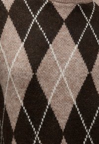 Tissu en laine tricotée à motif avec de grands losanges argyle marron et beige et de fines lignes croisées blanches.