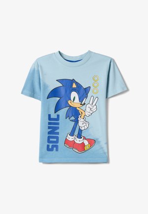 Lichtblauw T-shirt met Sonic the Hedgehog die een vredesteken maakt, drie gouden ringen en de tekst "SONIC" aan de voorkant.