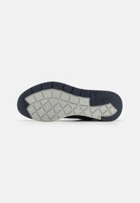 Semelle de sneaker présentant un motif texturé et segmenté en caoutchouc gris avec un accent bleu foncé ; conçue pour l'adhérence et la flexibilité.