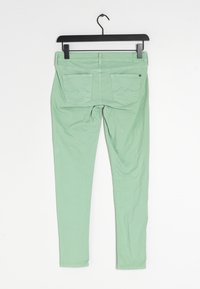 Skinny pants in mint green cotton, featuring two back pockets with wave stitch detailing. Smooth texture, minimalist design, and adjustable waistband.