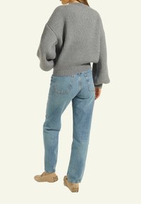 Grauer gerippter Pullover mit weitem Halsausschnitt und lockeren Ärmeln, kombiniert mit hellblauen Jeans im geraden Schnitt und beigen Slippern mit Akzenten.