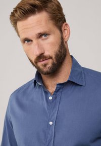 Blauwe button-up shirt van gladde stof, met een klassiek kraag en een enkele knoopsluiting, met een licht gekreukelde textuur.
