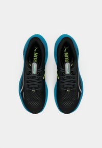 Black running shoes with a breathable mesh upper, teal accents, reflective details, and yellow logo, featuring a cushioned sole for comfort.