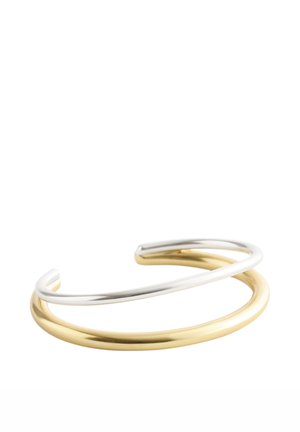 Åben manchetarmbånd med to overlappende glatte metalbånd, et sølvfarvet og et guldfarvet, på en hvid baggrund.