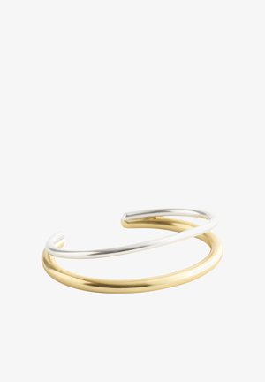 Open-ended armband met twee overlappende gladde metalen banden, één zilverkleurig en één goudkleurig, op een witte achtergrond.