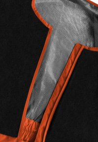 Musta kangas oranssilla reunuksella; sisältää verkko paneelin, jossa on timanttikuosi, integroitu elastisuus ja kokonaisuudessaan T-muotoinen muotoilu.