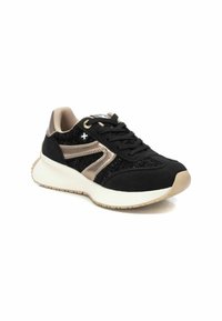 Zapatilla deportiva negra y beige con un acabado texturizado, que presenta un diseño con cordones, suela de goma y acentos metálicos en los laterales.
