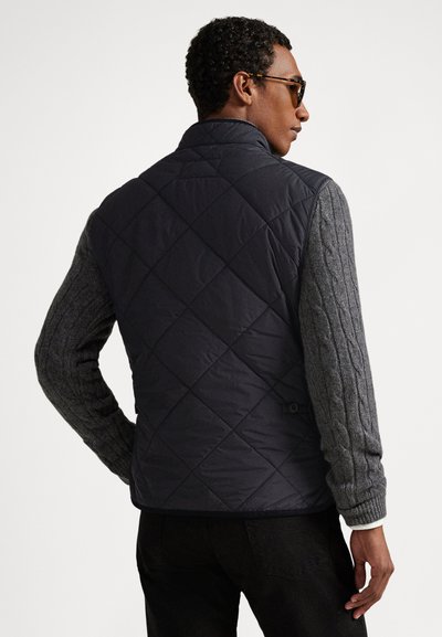 Prešívaná námornícka vesta s tmavosivými rukávmi s vzorom kabelového pletenia, vybavená stojacím golierom a nastaviteľnými pásokmi v páse. Hladké a štruktúrované materiály.