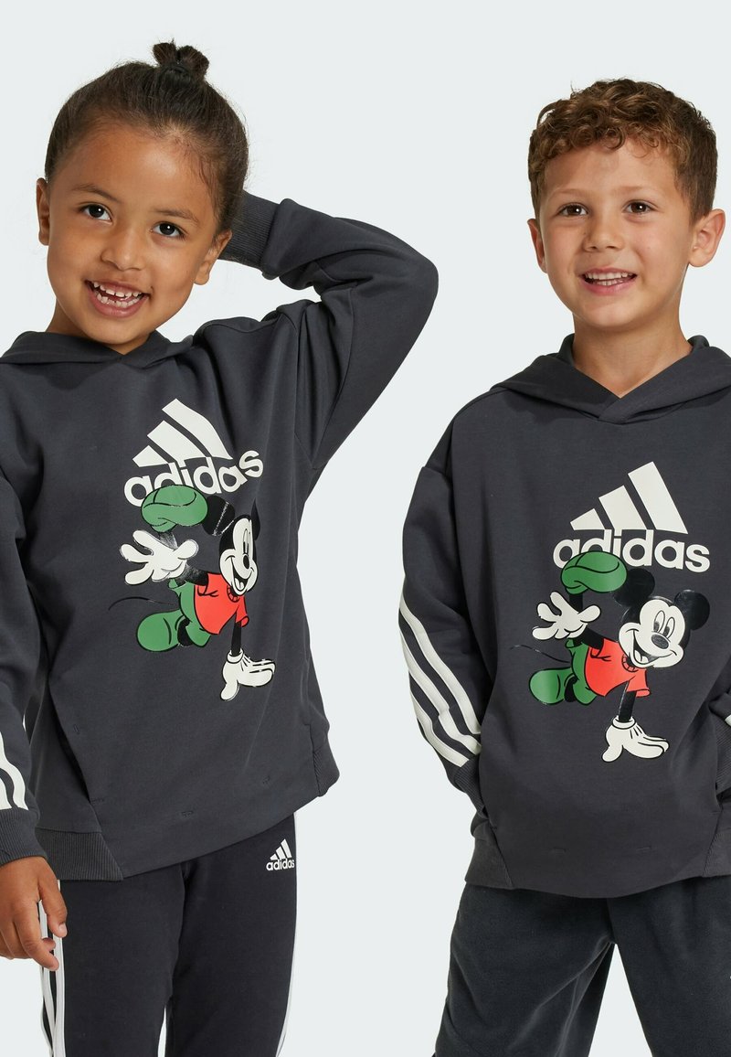 Felpe con cappuccio grigio scuro caratterizzate da una grande grafica di Topolino, tre strisce bianche sulle maniche e una texture del tessuto confortevole.