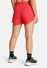 Punased spordirShorts elastse vöökohaga, siledast tekstuurist ja ümarate äärtega. Kombineeritud mustade spordijalatsite ja sokkidega.
