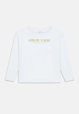 White long-sleeve shirt with gold "Calvin Klein New York City" text centered on the chest.