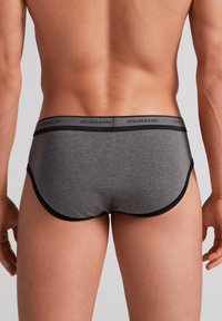 Grijze katoenen slip met een zwarte elastische tailleband met het merk "intimissimi". Kenmerkt zich door een gladde textuur en een slank ontwerp.