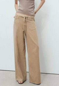 Wide-leg beige trousers with a drawstring waistband, made of soft fabric, featuring a smooth texture and minimalistic design.