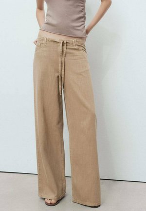 Wide-leg beige trousers with a drawstring waistband, made of soft fabric, featuring a smooth texture and minimalistic design.