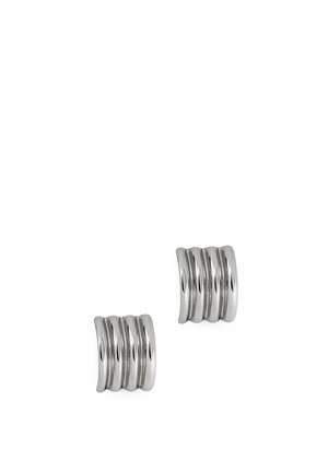 Paire de boucles d’oreilles argentées brillantes à clip avec un design incurvé et segmenté sur fond blanc.