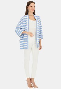 Lekkki, niebiesko-biały kimono w paski o luźnym kroju, z rękawami do trzech czwartych i kieszeniami z przodu. Teksturowana tkanina z kontrastowym wykończeniem.