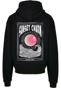 Felpa nera con cappuccio, caratterizzata da un design grafico sul retro con un sole rosa, onde oceaniche e il testo "SUNSET CHARM" in grassetto bianco.