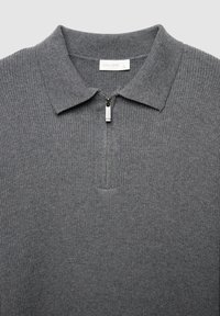 Grauer gestrickter Pullover mit einem Reißverschlusskragen, der über eine gerippte Textur und einen subtilen Glanz verfügt. Das Etikett trägt die Aufschrift "CALLIOPE", Größe L.