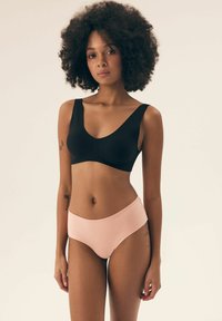Czarny bezszwowy biustonosz z szerokimi ramiączkami, połączony z jasnoróżowymi bezszwowymi majtkami typu hipster. Gładka tekstura, minimalistyczny design, brak widocznych elementów metalowych.