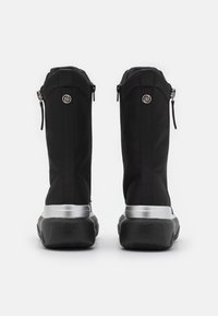 Botas negras hasta el tobillo con un elegante material superior, acentos metálicos y una suela gruesa negra. Presentan cremalleras laterales y un detalle de logotipo en la parte trasera.